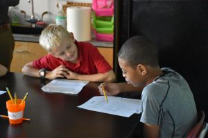 Two students sitting at a desk, completing their schoolwork