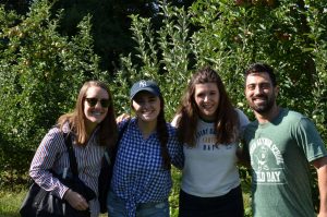 Four employees smiling together in front of trees