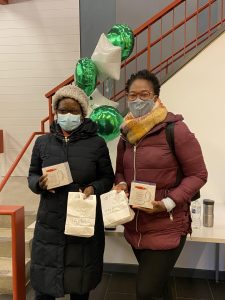 Two employees holding paper goodie bags