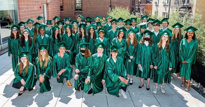 Group photo of the graduating class dressed in their green graduation caps and gowns.
