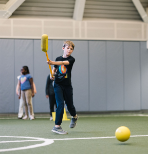 Student shooting ball into goal with hockey stick