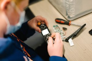 Student takes a cellphone apart using a screwdriver