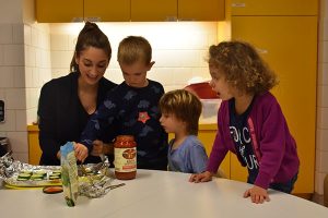 EC students spreading tomato sauce on top of sliced zucchini in a baking tray