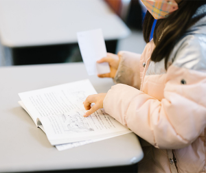 Students points at a book's pages as they read