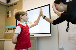 Student smiles up at teacher and meets her in a high five
