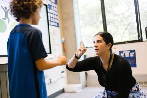 Teacher holds up one finger to student, to indicate number of syllables