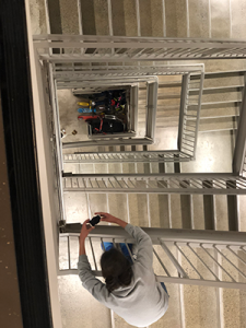 Students lowers their device down to the first floor of the stairwell