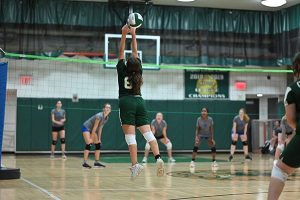 Female volleyball player jumps up to touch the ball