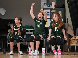 Members of the Gaynor volleyball team sitting on the side of the court cheering on their teammates