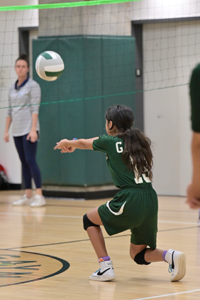 Gaynor volleyball player kneels down to bump the ball