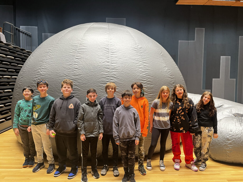 A Green Cluster class poses together outside of the StarLab.