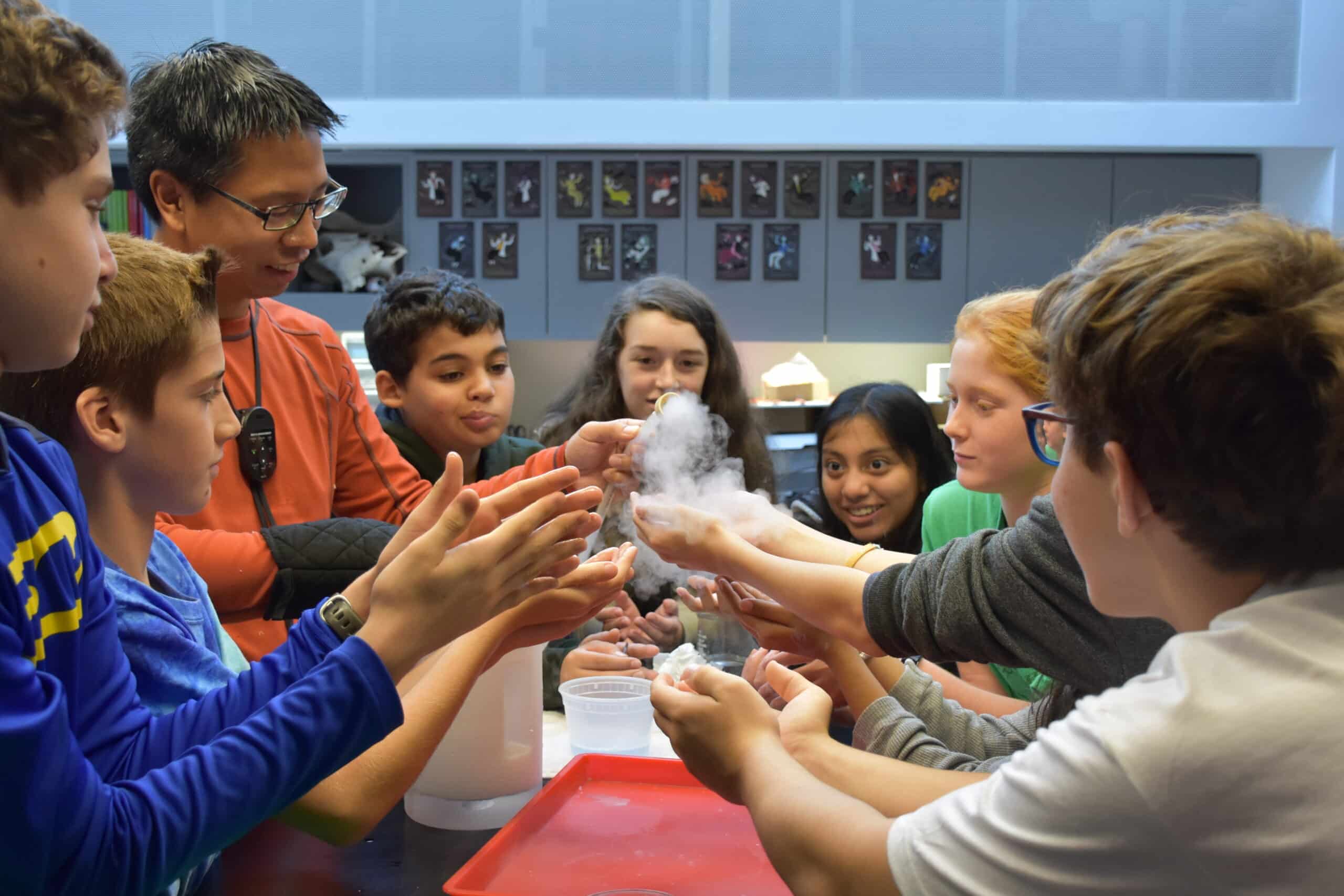 Andrew Prasarn holding a block of liquid nitrogen up to students gathered around a table.